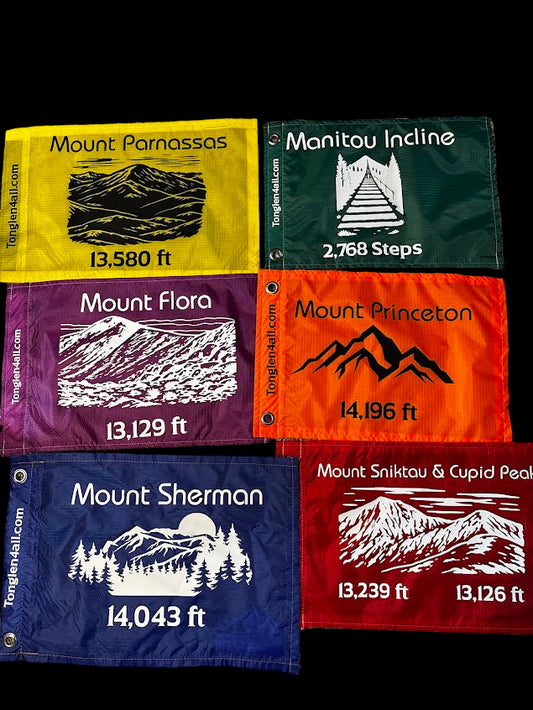 Set of hiking flag reproductions with mountain names and heights on a textured surface