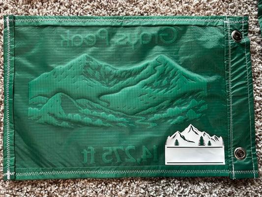 Green fabric with embroidered design and brand logo on a textured surface