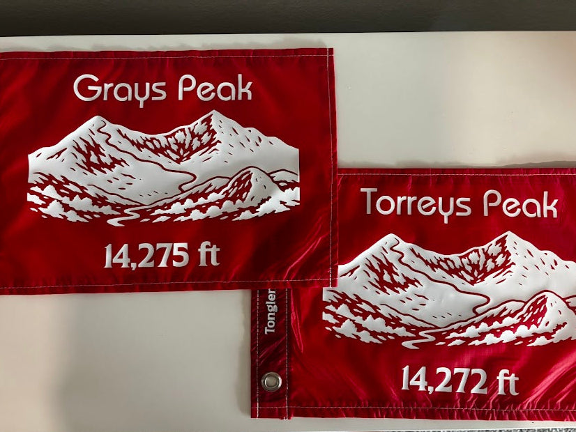Two red flags with white mountain designs and text on a white background