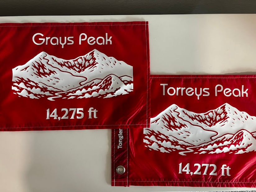 Two red flags with white mountain designs and text on a white background