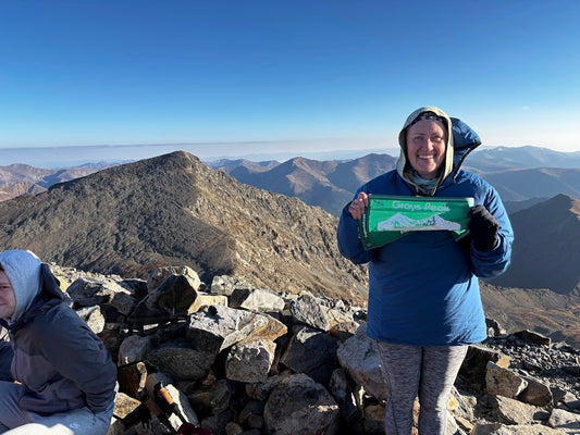 Person holding a certificate on a mountain peak with scenic view