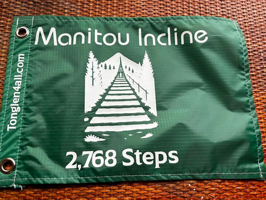 Green fabric flag with 'Manitou Incline' and '2,768 Steps' white text 