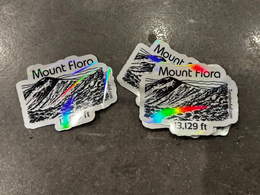 Two mountain-themed stickers on a textured surface with visible text.